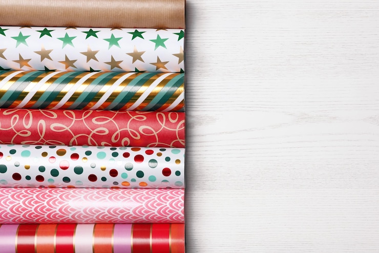 Photo different colorful wrapping paper rolls on white wooden table flat lay space for text