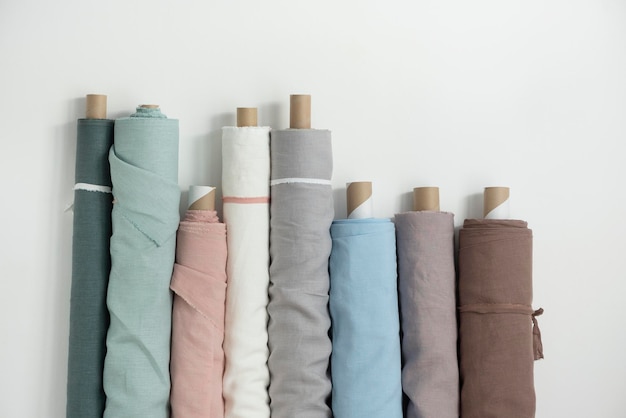 Photo different colors fabric linen rolls on the white walls selective focus image