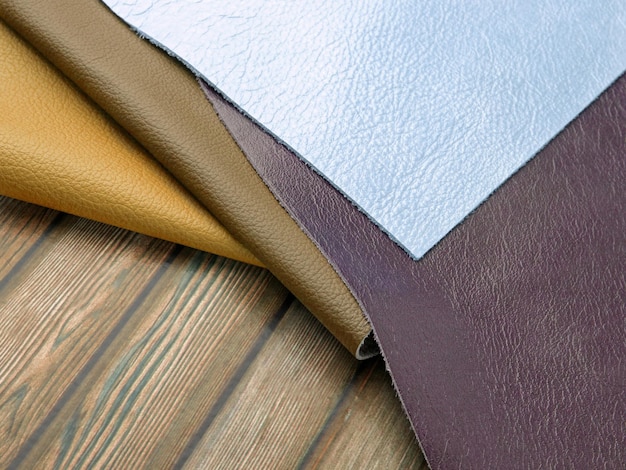 Different colors natural leather textures samples on brown wooden background