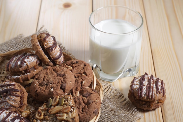 Different cookies and a glass with milk for breakfast on a wooden table