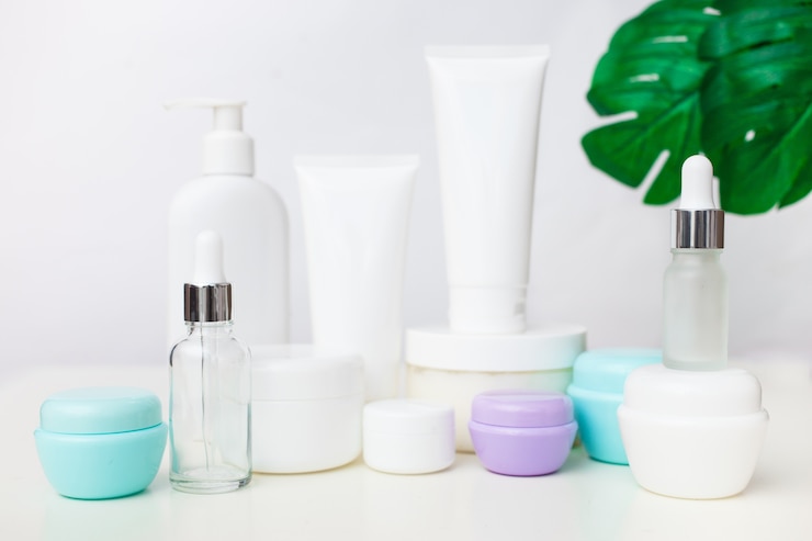 Photo different cosmetic bottles on white background with leaves. set of cosmetic products. cosmetic package collection for cream, soups, foams, droppers.