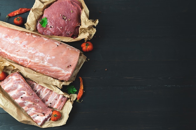 Different cuts of meat, fresh on a dark background.