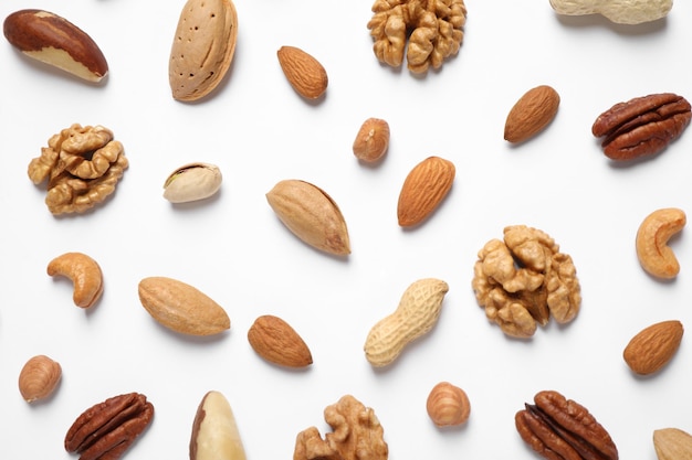 Different delicious nuts on white background flat lay