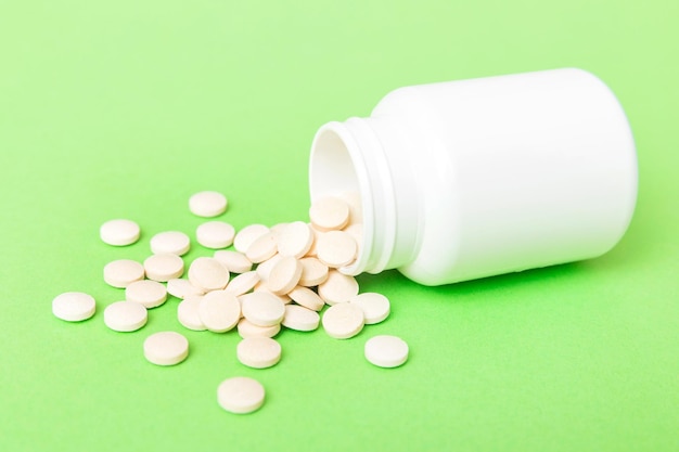 Different drugs and health supplement pills poured from a medicine bottle health care and medical top view on colored background