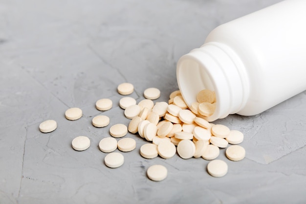 Different drugs and health supplement pills poured from a medicine bottle health care and medical top view on colored background