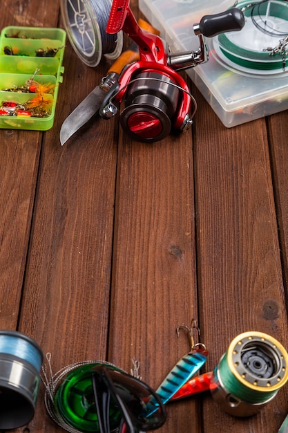 Different fishing tacles with lures and reels on wooden brown background with place for text. Design for advertisment and publishing.