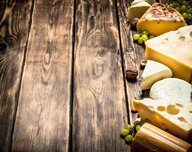 Different flavored cheeses with walnuts and white grapes .