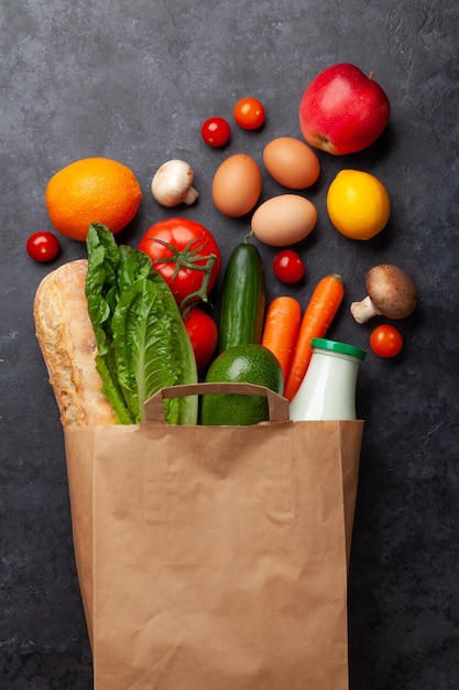 Different food in recycling paper bag on stone table Top view flat lay with copy space