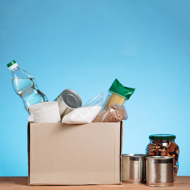 Different food in a volunteer box. Donate Box, donaation and charity concept. Donation box with food on blue background. square image