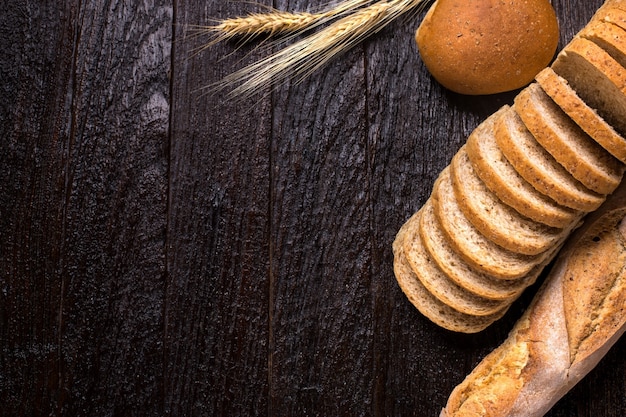 Different fresh bread, on old wooden table and copy space for text, dark tone