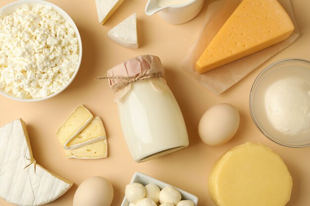 Different fresh dairy products on beige background, top view