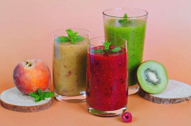 different fresh healthy smoothies in a glasses made of peach, banana and berries with mint. Drinks