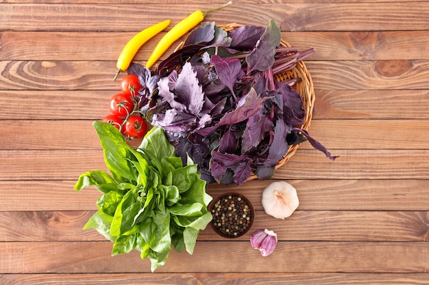 Different fresh herbs with vegetables and spices on wooden table