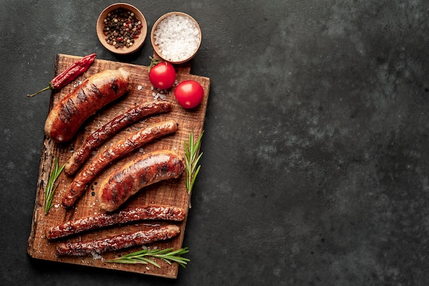 different fried sausages with spices and rosemary, on a stone table, ready to eat 