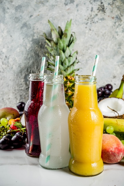 Different fruit juices smoothies concept, summer vitamins diet, with tropical fruits and berries on a light background,