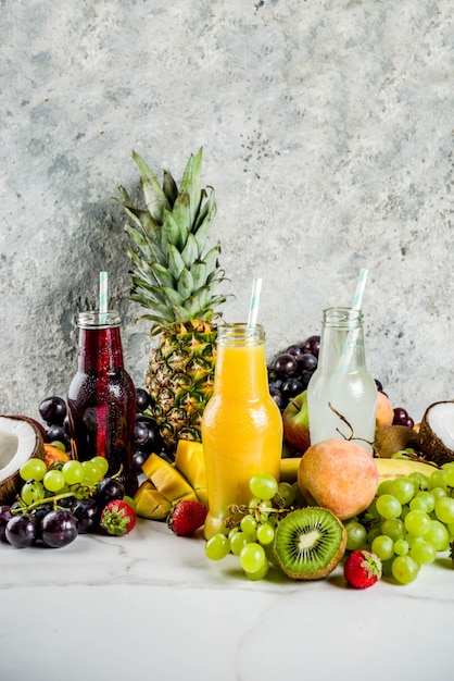 Different fruit juices smoothies concept, summer vitamins diet, with tropical fruits and berries on a light background,