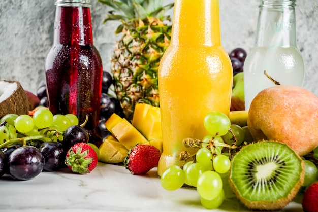 Different fruit juices smoothies concept, summer vitamins diet, with tropical fruits and berries on a light background,