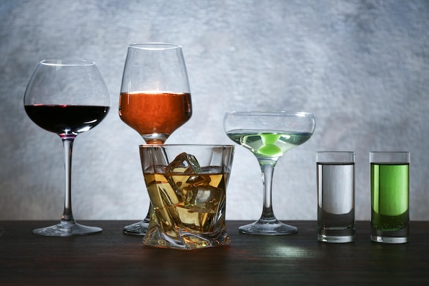 Photo different glasses of wine and spirits on color background