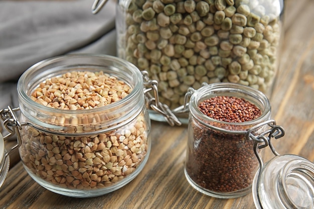 Different grains in glass jars on wooden table