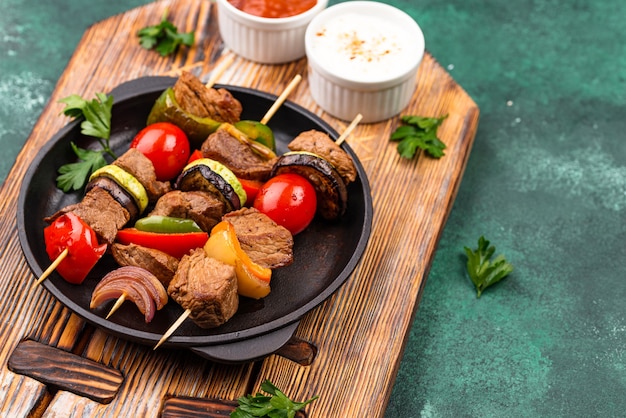 Different grilled kebabs with meat, mushrooms, sausages and vegetable on skewers