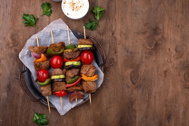 Diversi spiedini alla griglia con carne, funghi, salsicce e verdure su spiedini