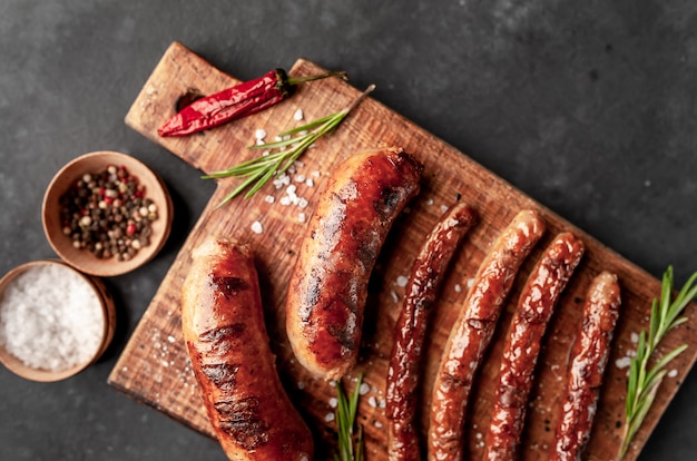 different grilled sausages with spices and rosemary, on a stone table ready to eat