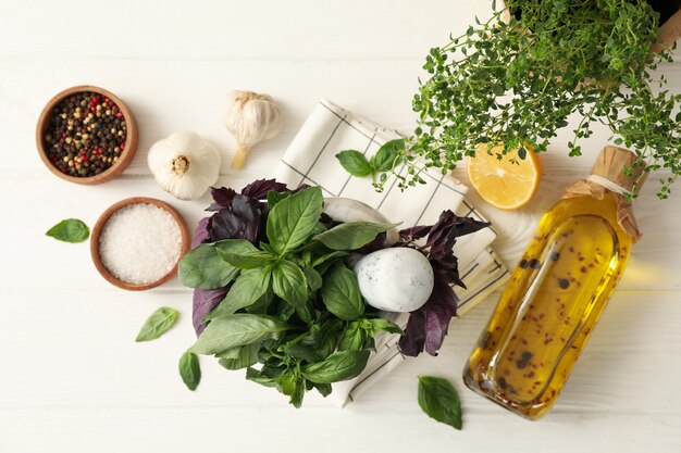 Diverse erbe, olio e spezie su fondo di legno bianco, vista dall'alto