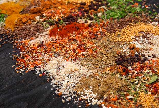 Different herbs and spices on black wooden. Closeup