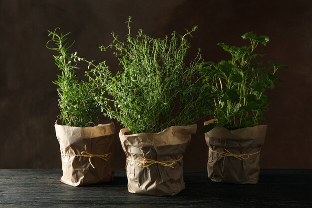 Different herbs on wooden table against brown background