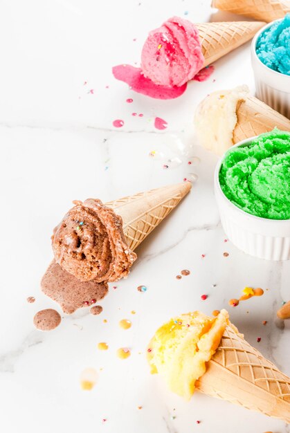 Different homemade melting ice cream in bowls and waffle ice cream cones