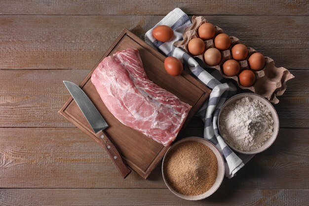 Photo different ingredients for cooking schnitzel on wooden table flat lay