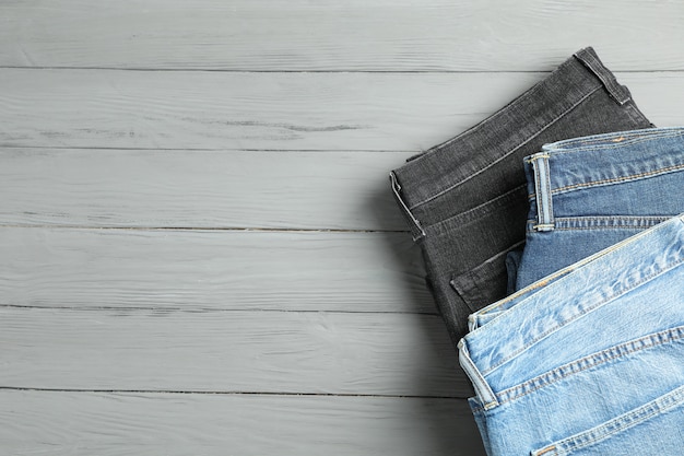 Different jeans on grey wooden table