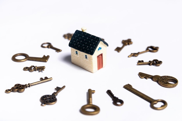 Photo different keys and a little house on a white background, concept of real estate