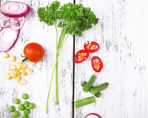 Different kind of raw vegetables on wooden table