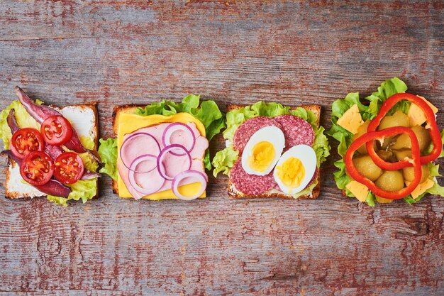 Different kind of sandwich on a wooden background