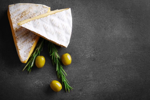 different kinds of cheese olives and rosemary on grey background copy space