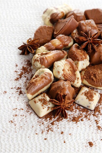 Different kinds of chocolates with spices on white background