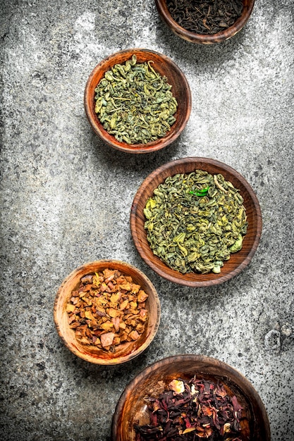 Different kinds of fragrant tea in bowls on a rustic background