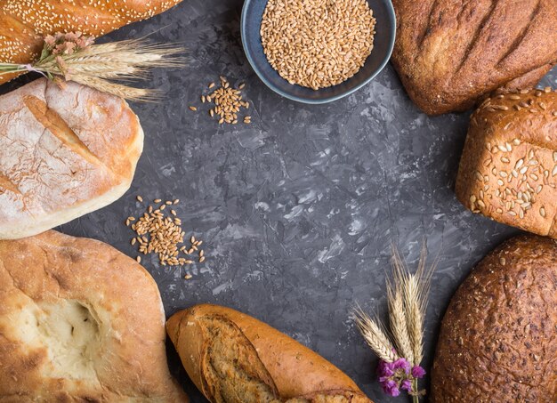 Different kinds of fresh baked bread on a black concrete background. top view, copy space.