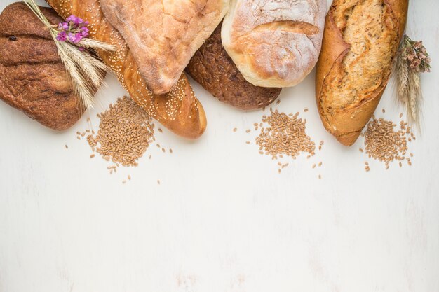 Different kinds of fresh baked bread on a white wooden background. top view, copy space.