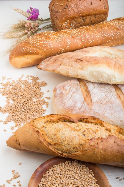 Diversi tipi di pane appena sfornato su una superficie di legno bianca. vista laterale.