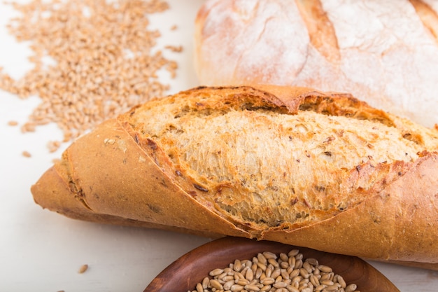 Different kinds of fresh baked bread on a white wooden surface. side view.