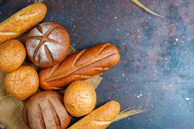 Different kinds of fresh bread as background, top view