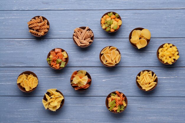 Photo different kinds of pasta in bowls on wooden background