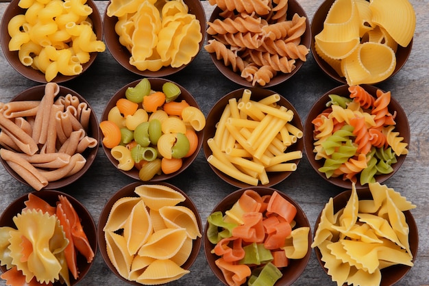 Foto diversi tipi di pasta in ciotole su fondo di legno