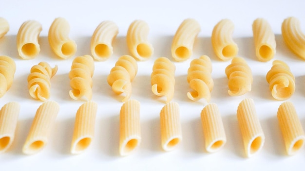 Photo different kinds of raw pasta on white background vegetarian food knolling concept