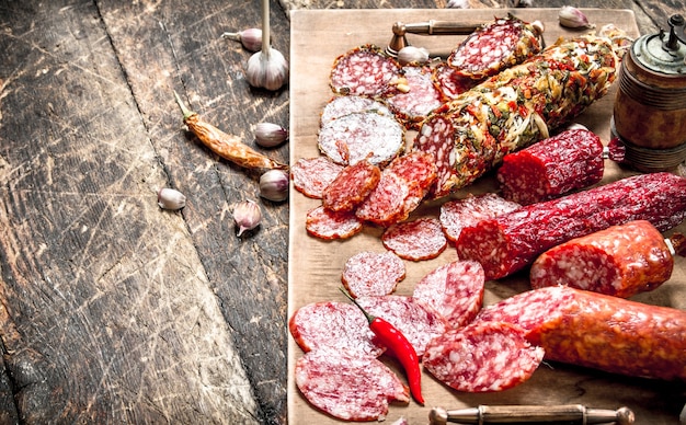 Different kinds of salami on the boards. On a wooden background.