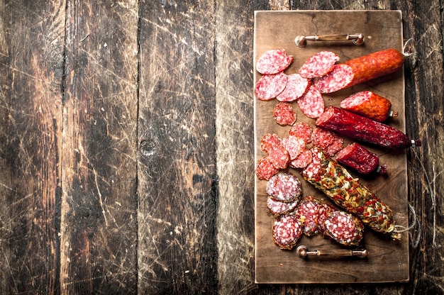 Different kinds of salami on the boards on a wooden background