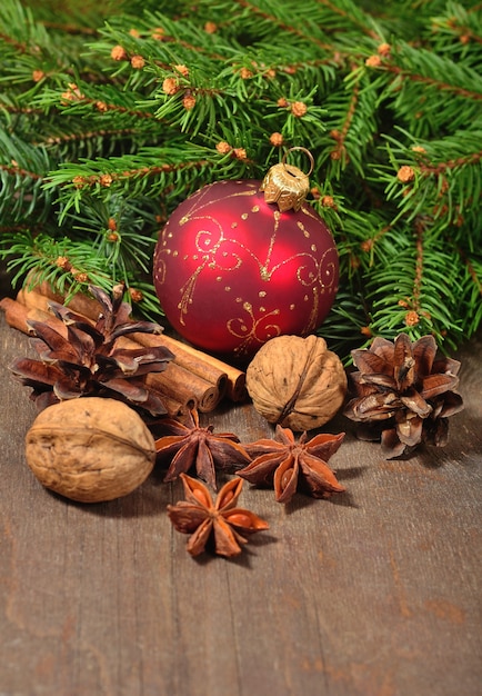 Different kinds of spices nuts cones Christmas decorations and spruce branch on a wooden background