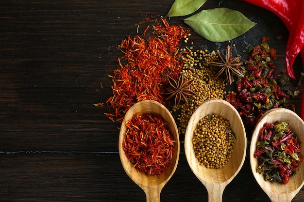 different kinds of spices in spoons closeup on wooden background